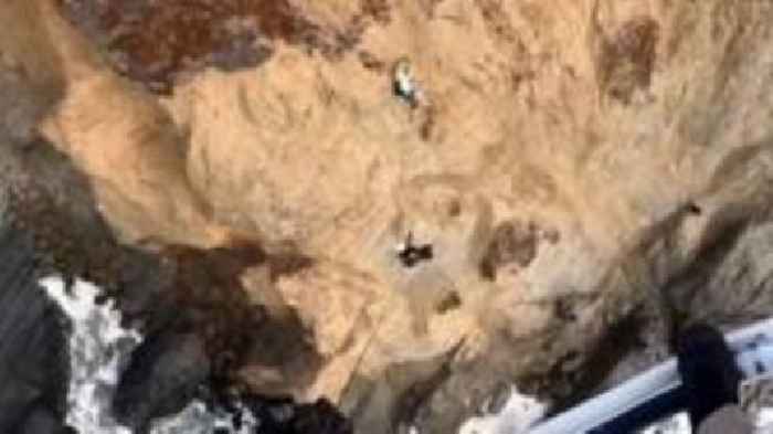 Moment person clinging to cliff is rescued by helicopter