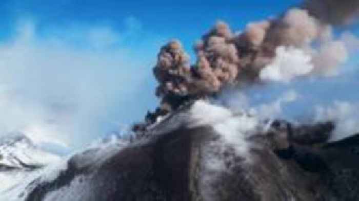 Lava and smoke emerge from a snowy Mount Etna