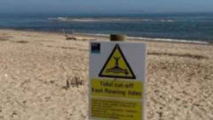 Tide cut-off warning signs over sandbank